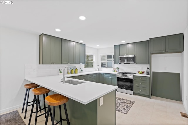 kitchen featuring a breakfast bar, sink, kitchen peninsula, stainless steel appliances, and backsplash