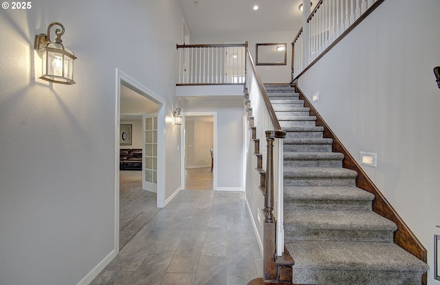 stairway with recessed lighting, french doors, baseboards, and a towering ceiling