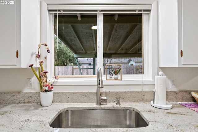 room details with sink, white cabinets, and light stone counters