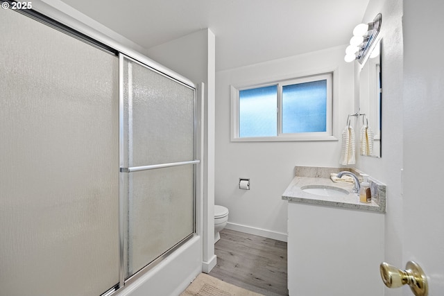 full bathroom featuring bath / shower combo with glass door, vanity, toilet, and hardwood / wood-style floors