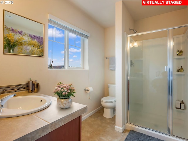 bathroom featuring tile patterned flooring, a shower stall, baseboards, toilet, and vanity