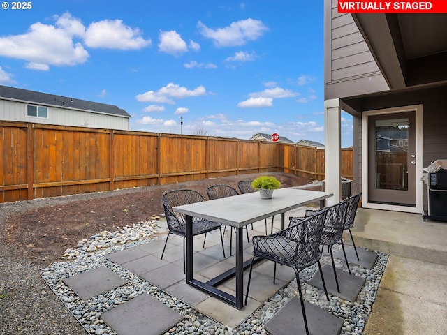 view of patio with outdoor dining area, a fenced backyard, and a grill