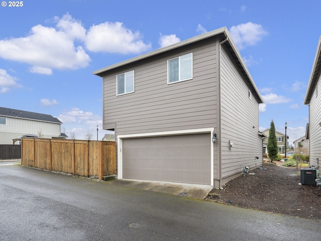 exterior space with central air condition unit, fence, and a garage