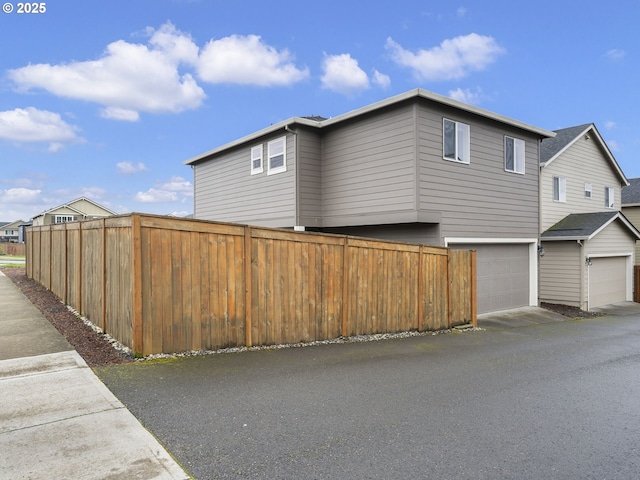 view of home's exterior with an attached garage and fence