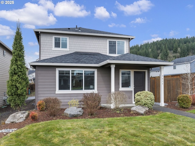 view of front of property featuring a front lawn, fence, and roof with shingles