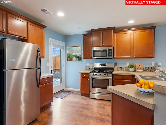 kitchen featuring visible vents, light countertops, light wood-style flooring, appliances with stainless steel finishes, and a sink