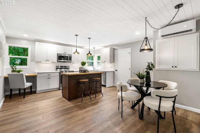 91822 Rulyville Rd, Westport, OR 97016 - kitchen with appliances with stainless steel finishes, an AC wall unit, a center island, tasteful backsplash, and recessed lighting