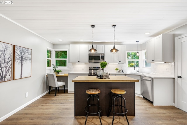 91822 Rulyville Rd, Westport, OR 97016 - kitchen featuring appliances with stainless steel finishes, wooden counters, a sink, backsplash, and a breakfast bar area