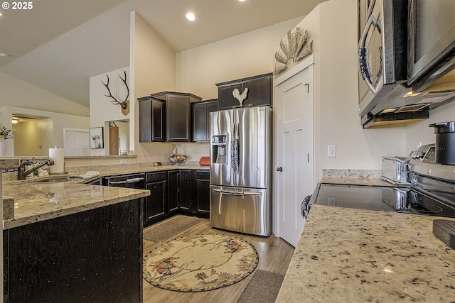 10764 Wiseacre Ln NE, Aurora, OR 97002 - kitchen with appliances with stainless steel finishes, a sink, light stone counters, light wood-style flooring, and vaulted ceiling
