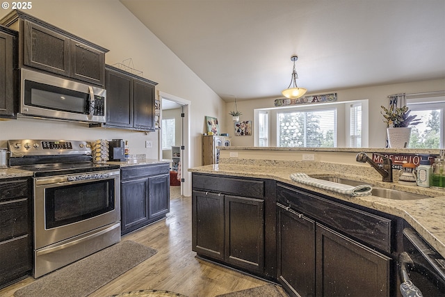 10764 Wiseacre Ln NE, Aurora, OR 97002 - kitchen with appliances with stainless steel finishes, a sink, light wood finished floors, lofted ceiling, and light stone counters