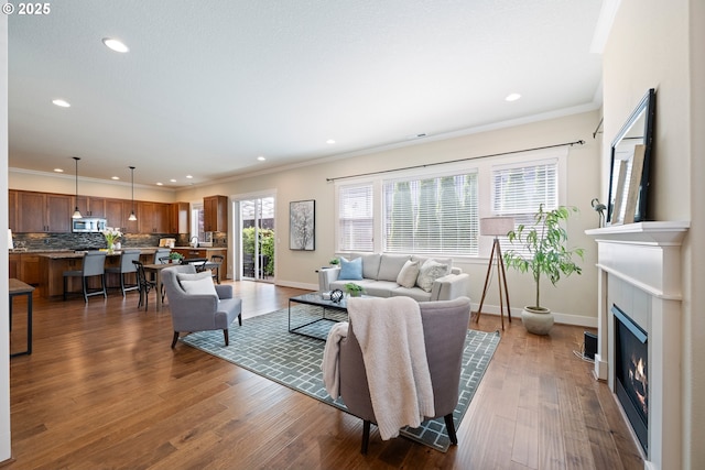 15152 NW Marie Way, Portland, OR 97229 - living room featuring recessed lighting, crown molding, baseboards, a glass covered fireplace, and dark wood-type flooring