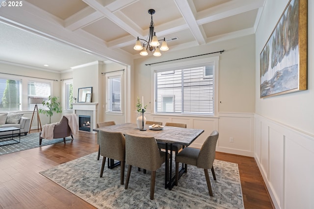 15152 NW Marie Way, Portland, OR 97229 - dining space featuring a warm lit fireplace, a chandelier, beam ceiling, dark wood finished floors, and a wainscoted wall