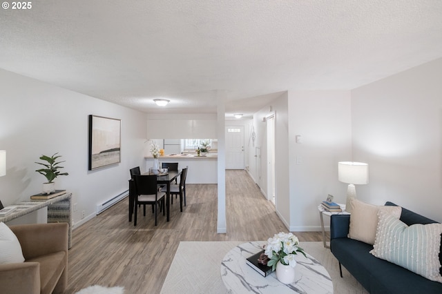 living room with baseboards, a textured ceiling, light wood-style flooring, and a baseboard heating unit