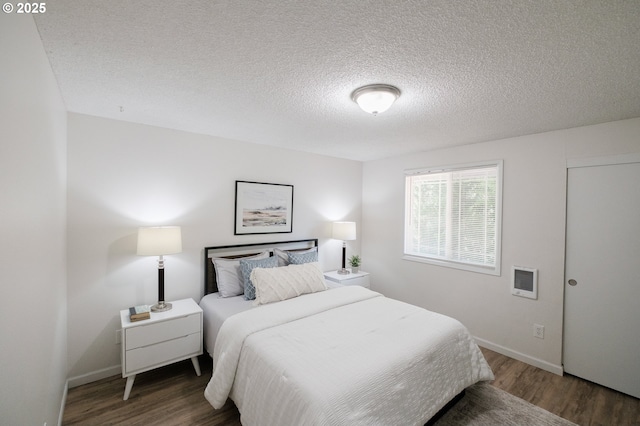 bedroom featuring a textured ceiling, baseboards, and wood finished floors