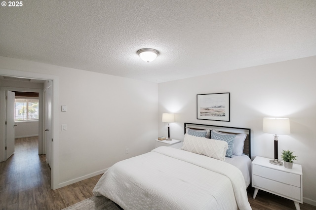 bedroom featuring a textured ceiling, baseboards, and wood finished floors