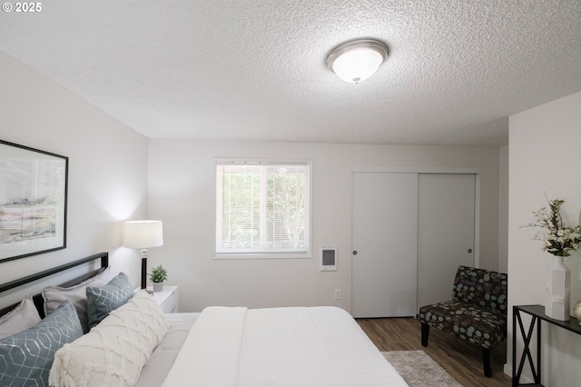bedroom with a textured ceiling, a closet, and wood finished floors