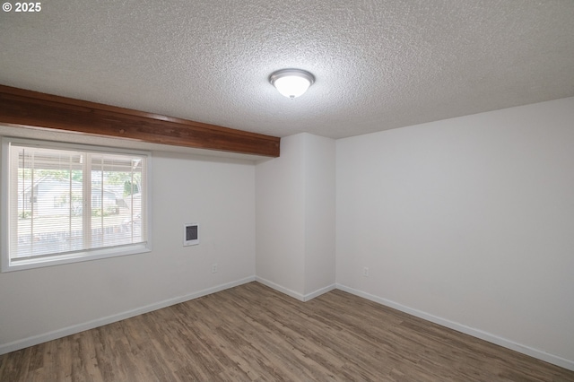 empty room with baseboards, a textured ceiling, and wood finished floors