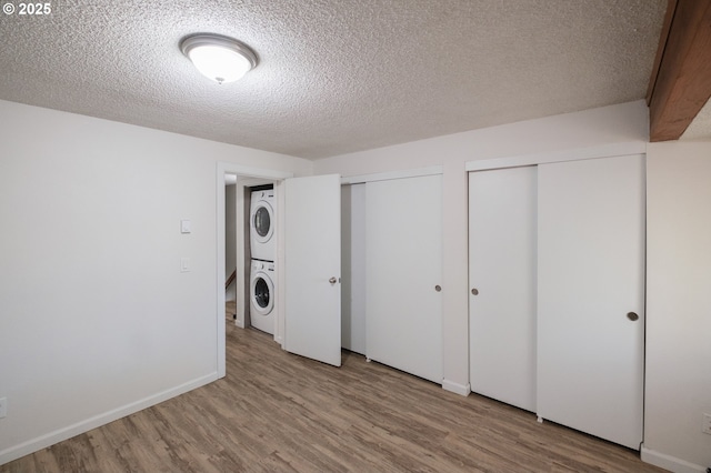 interior space featuring wood finished floors, laundry area, a textured ceiling, and stacked washer / drying machine