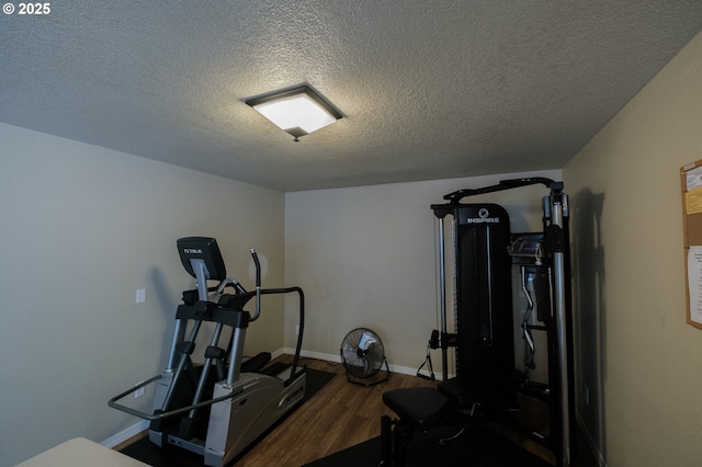 exercise room with a textured ceiling, baseboards, and wood finished floors
