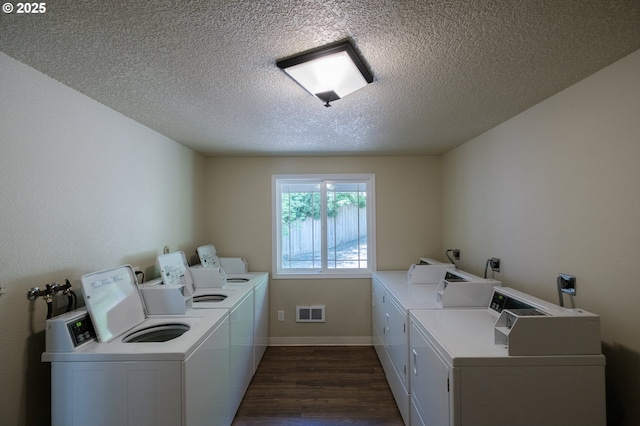shared laundry area with separate washer and dryer, dark wood-style floors, a textured ceiling, and visible vents