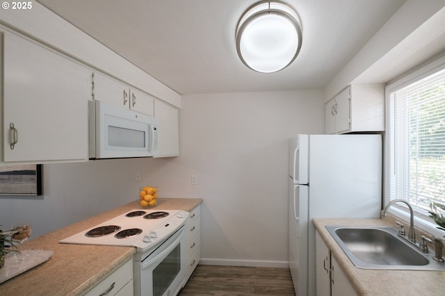 kitchen featuring wood finished floors, a sink, light countertops, white cabinets, and white appliances