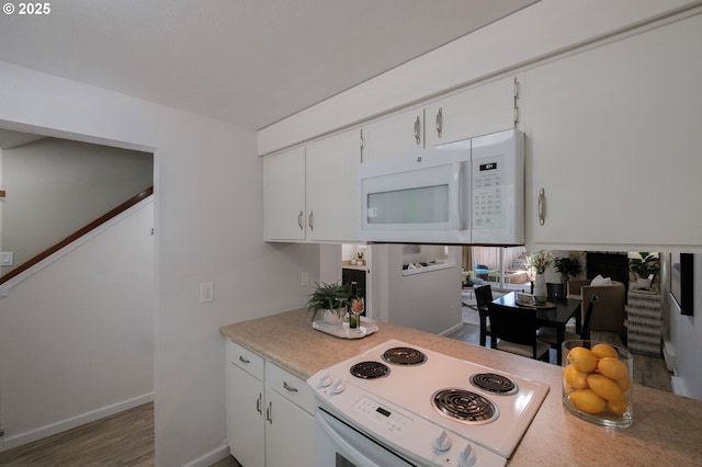 kitchen with light countertops, white cabinets, white appliances, and wood finished floors