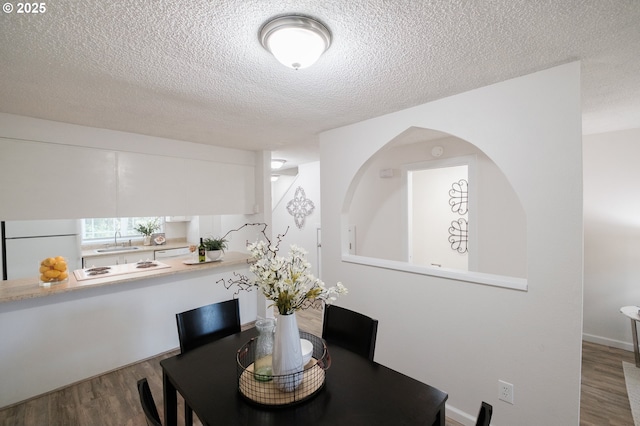 dining space with a textured ceiling and wood finished floors