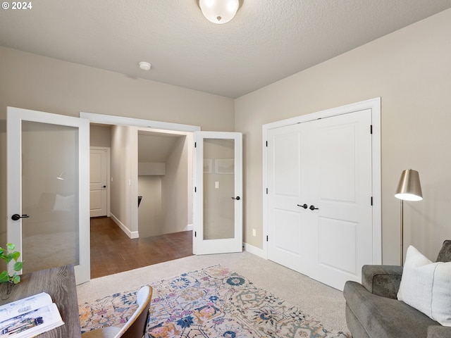 interior space with a textured ceiling, french doors, a closet, and baseboards