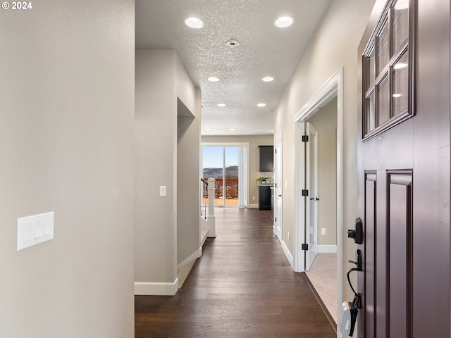 hall featuring recessed lighting, dark wood finished floors, a textured ceiling, and baseboards