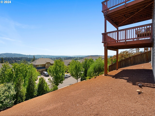 view of yard featuring a deck with mountain view and fence