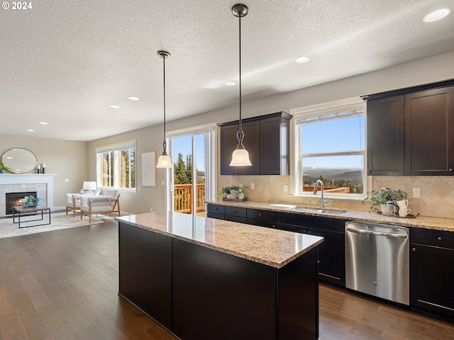 kitchen featuring a center island, dark wood-style flooring, a tiled fireplace, stainless steel dishwasher, and open floor plan