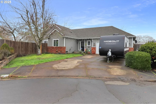 view of front of property with a shingled roof, fence, concrete driveway, and brick siding