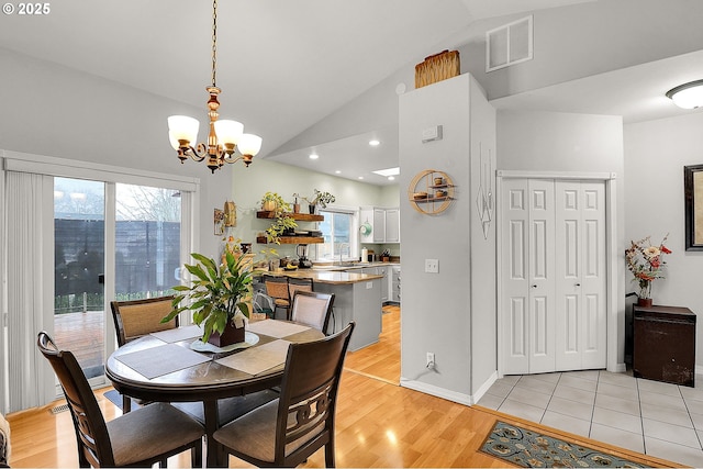 dining area featuring light wood finished floors, visible vents, vaulted ceiling, a chandelier, and baseboards