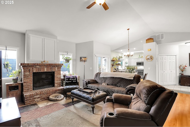 living room featuring a brick fireplace, visible vents, plenty of natural light, and light wood-style flooring