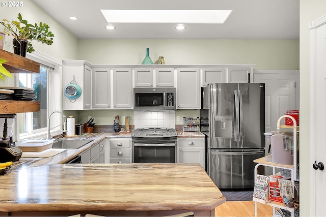 kitchen featuring white cabinetry, a skylight, and appliances with stainless steel finishes