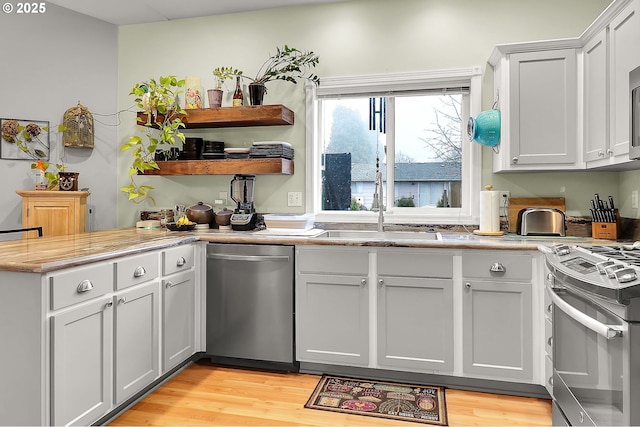 kitchen with stainless steel appliances, sink, light hardwood / wood-style flooring, and white cabinets