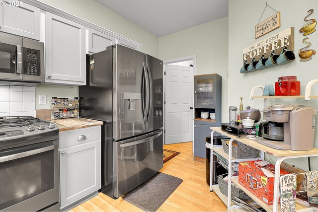 kitchen with tasteful backsplash, light hardwood / wood-style flooring, stainless steel appliances, and white cabinets