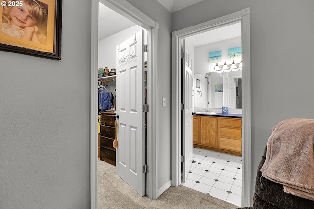 bathroom with a walk in closet, vanity, and tile patterned floors