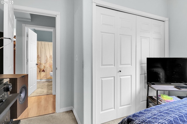 bedroom with light wood-style floors, a closet, and baseboards