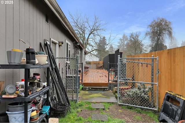 view of yard with a gate, fence, an outbuilding, and a wooden deck