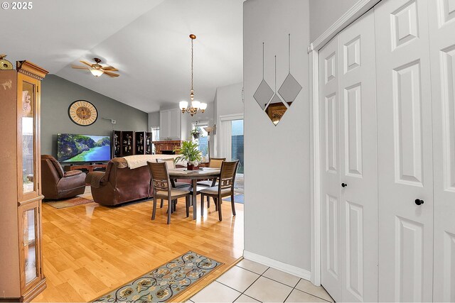 dining room featuring ceiling fan with notable chandelier, lofted ceiling, and light hardwood / wood-style floors