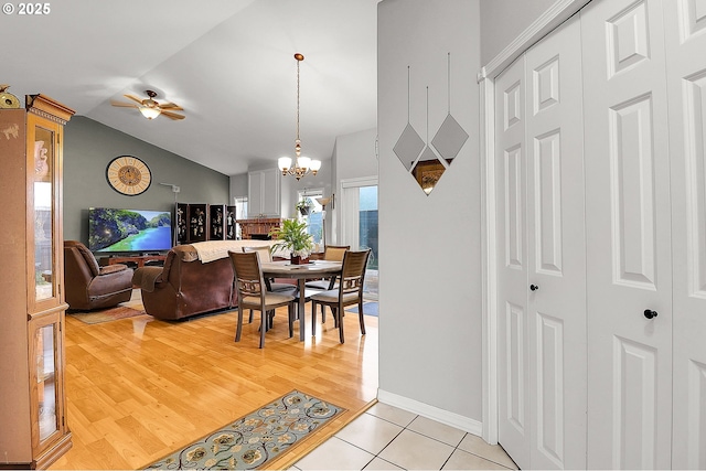 dining space featuring lofted ceiling, light wood-style floors, baseboards, and ceiling fan with notable chandelier