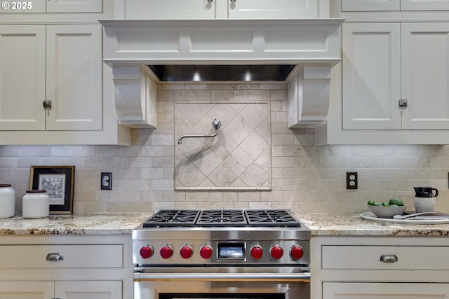 kitchen featuring stainless steel range, white cabinetry, and backsplash