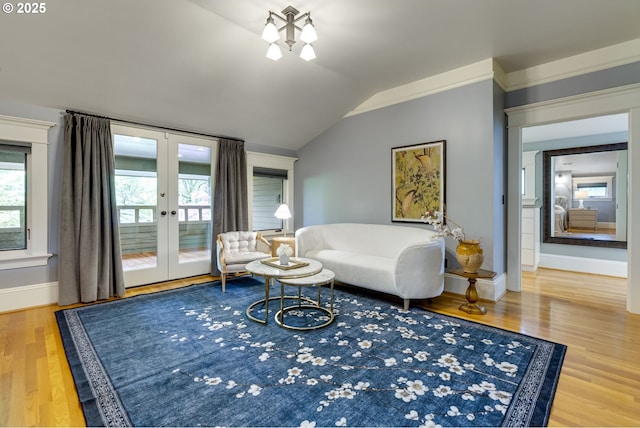 living area featuring french doors, vaulted ceiling, wood finished floors, and baseboards