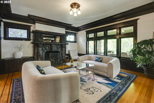 living room featuring crown molding, hardwood / wood-style floors, and a stone fireplace