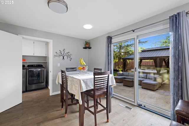 dining space with visible vents, light wood-style flooring, and independent washer and dryer