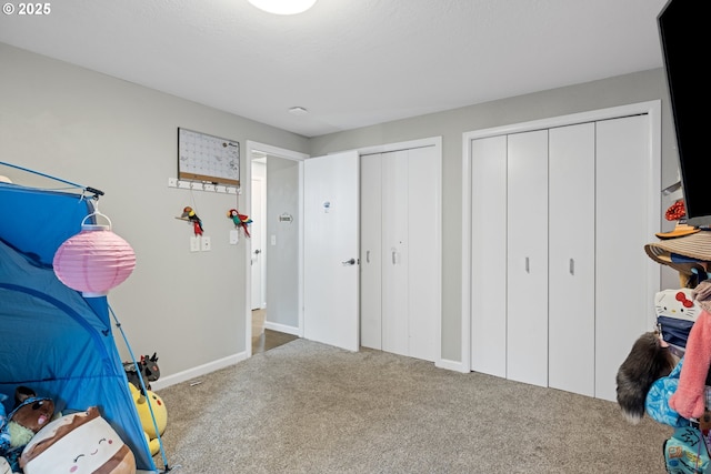 carpeted bedroom featuring baseboards and multiple closets