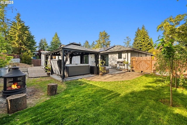 back of property featuring a hot tub, a gazebo, a fenced backyard, and a patio area