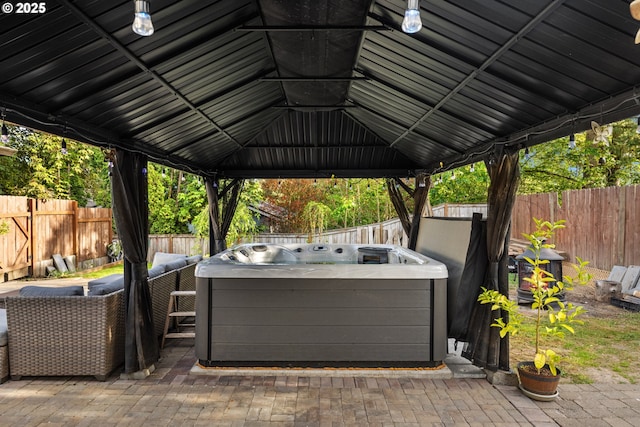 view of patio / terrace with washer / clothes dryer, a fenced backyard, a hot tub, and a gazebo