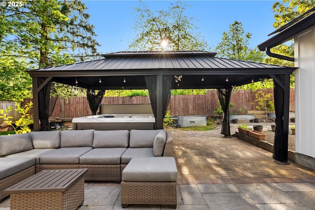 view of patio / terrace with a fenced backyard, a hot tub, a gazebo, and an outdoor living space